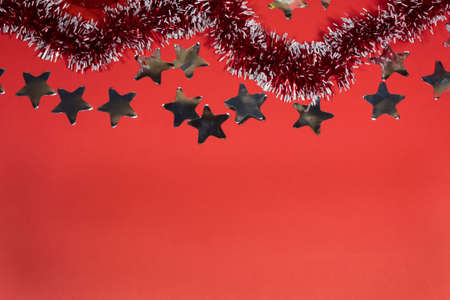 Red glittering tinsel and silvery stars lie on a red background.