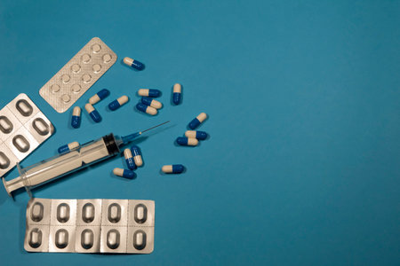 On a blue background pills in plates, capsules and syringe.の写真素材