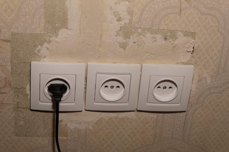 Three electrical points have been inserted into the wall and putty, into one of which the plug of...
