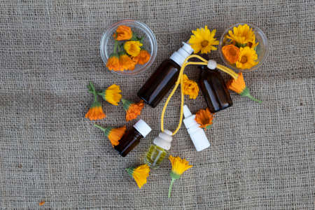 Calendula flowers, bottles and oil lie on a jute fabric.の写真素材