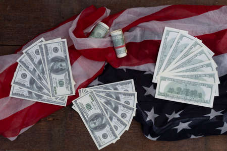 One hundred dollar bills are spread out against the background of the American flag.の写真素材