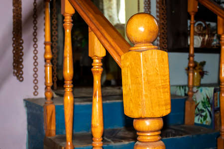 Fragment of a wooden staircase in a country house. The first support post with a ball is made in the...