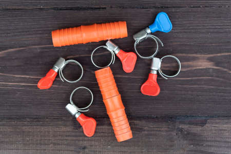 On a dark wooden background, there are grommets and clamps for connecting garden irrigation hoses.の写真素材