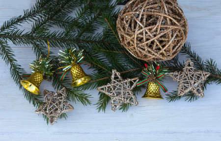 Christmas background. Fir-tree branches, bells, a shiny ball and stars lie on a white background.