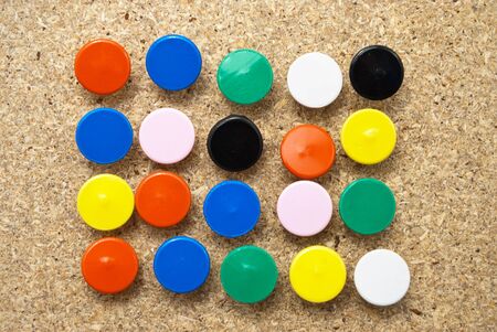 Colorful thumbtacks in a wooden board.