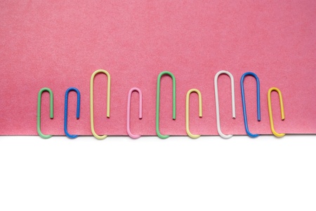 Some clips on pink paper against the white background.の写真素材