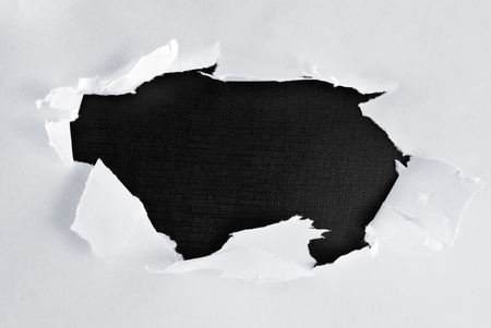 Breakthrough paper hole with black textured background.の写真素材