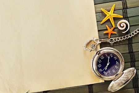 Marine themed frame of paper sheet, watches and seashells on a wooden mat.の写真素材