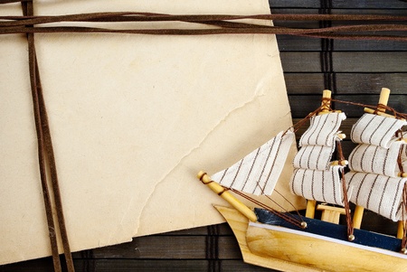 Marine theme frame of paper sheet and little ship on a wooden mat.