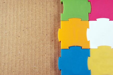 Few colorful empty puzzles on a cardboard background.