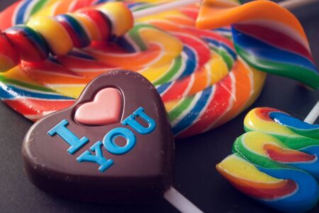 Few colorful lollipops and chocolate heart against gray background.の写真素材