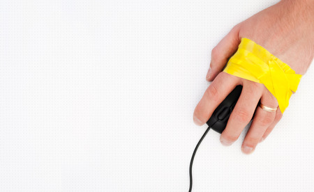 A hand of men on a computer mouse tied with yellow adhesive tape.の写真素材