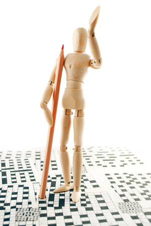 Classic wooden dummy with red pencil and crossword puzzles.の写真素材