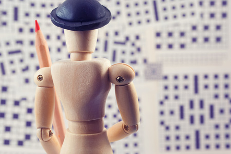 Classic wooden dummy with red pencil and crossword puzzles.の写真素材