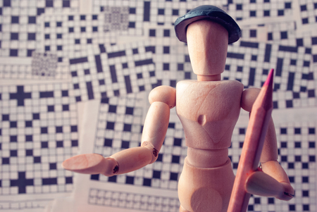 Classic wooden dummy with red pencil and crossword puzzles.の写真素材