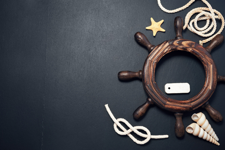 Marine composition of decorative steering wheel and sailor ropes with few other items on a...