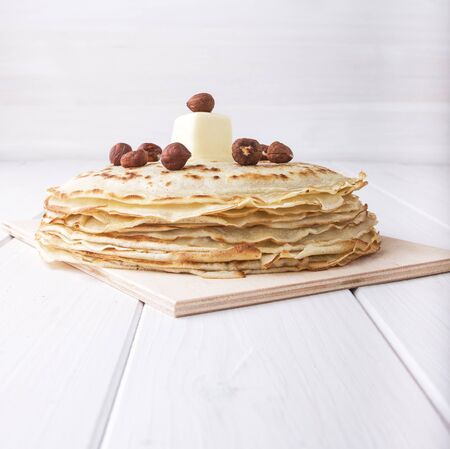 Close-up pancakes with hazelnut and butter on white wooden background