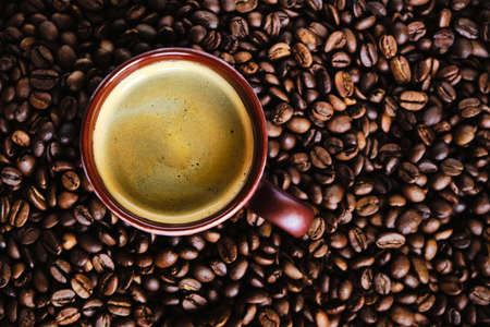 Coffee cup with free space for text on roasted coffee beans close up