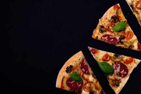 Hot and delicious pizza slices ready to eat on a black wooden backgroundの写真素材