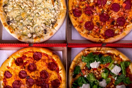 Four different pizza in boxes - Caesar, with salami and chicken. Top viewの写真素材