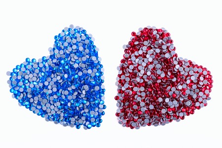 A lot of red and blue rhinestones made in the shape of a heart on a white background. Top view