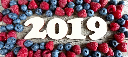 Year 2019 with blueberries and raspberries on a wooden background. Top view.の写真素材