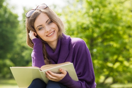 Beautiful girl reading a book and relax in the parkの写真素材