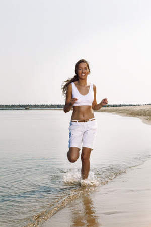 Female runner jogging during outdoor workout on beachの写真素材