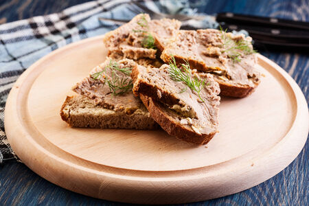 Slices of bread with baked pate on wooden board