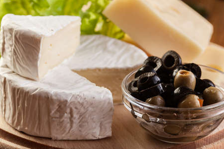 Cheese, olive and grapes on wooden boardの写真素材