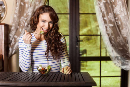 Pretty woman eating fresh vegetable saladの写真素材