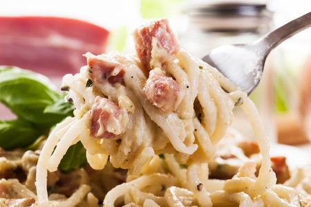 Spaghetti carbonara with bacon and basil on a plateの写真素材