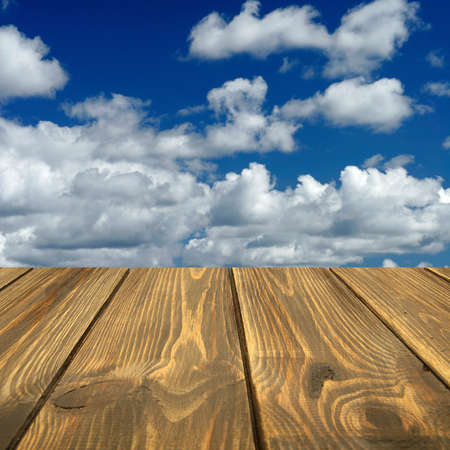 Old wooden table and clouds in the background