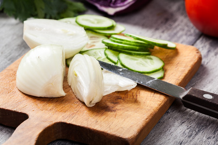 Chopped vegetables: onion and cucumber on cutting board. Selective focusの写真素材