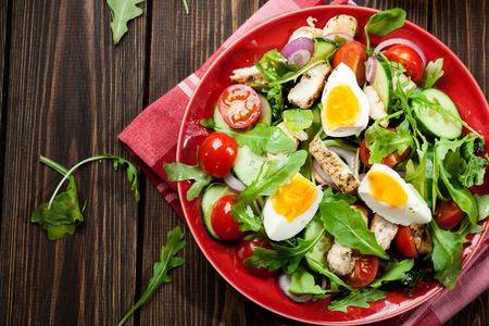 Fresh salad with chicken, tomatoes, eggs and arugula on plate. Healthy foodの写真素材