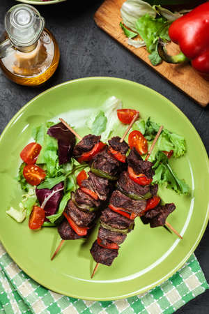 Grilled beef meat and vegetable kebabs on the green plateの写真素材