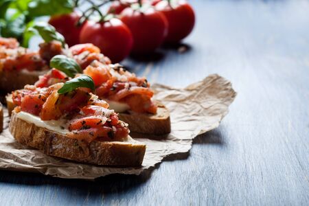 Italian bruschetta with roasted tomatoes, mozzarella cheese and herbs on a paperの写真素材