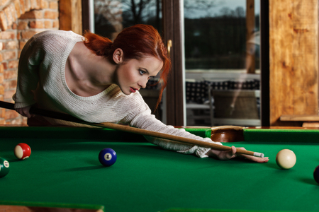Young attractive woman plays the game of snooker pool tableの写真素材