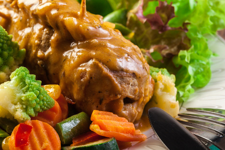 Pork rolls with prepared potatoes and vegetables on plateの写真素材