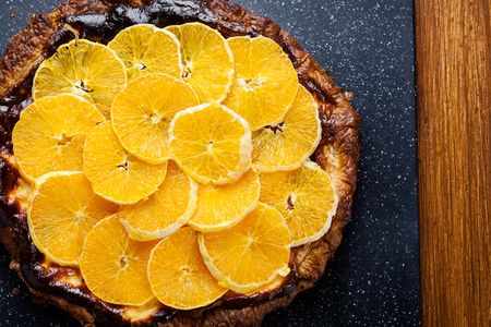 Delicious tart with cottage cheese and sliced orange on cutting boardの写真素材