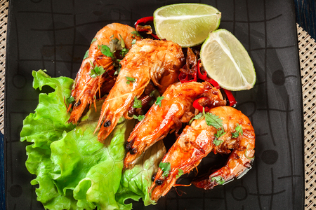 Shrimps roasted with onion, garlic and chili served on black plate.の写真素材