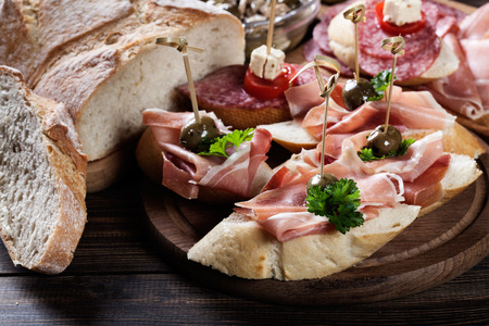 Spanish tapas with slices jamon serrano, salami, olives and cheese cubes on a wooden table. Spanish cuisineの写真素材
