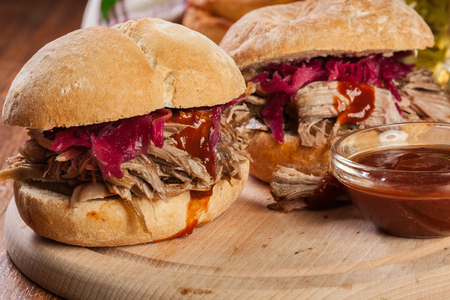 Pulled pork sandwich with red cabbage and bbq sauce on cutting boardの写真素材