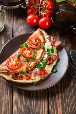 Omelette with bacon and tomatoes on brown plate. Top viewの写真素材