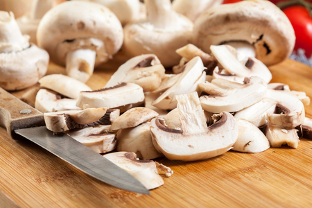 Fresh sliced white mushrooms on cutting board ready for fryingの写真素材