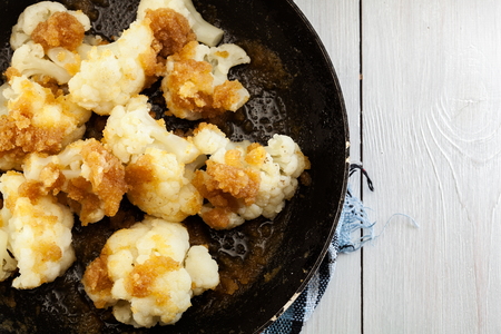 Vegetarian fried cauliflower with bread crumb and butter on frying panの写真素材