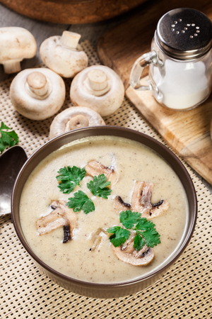 Mushroom cream soup with herbs and spices in brown bowlの写真素材