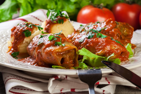 Stuffed cabbage with meat and rice served with boiled potatoes and tomato sauce on white plateの写真素材