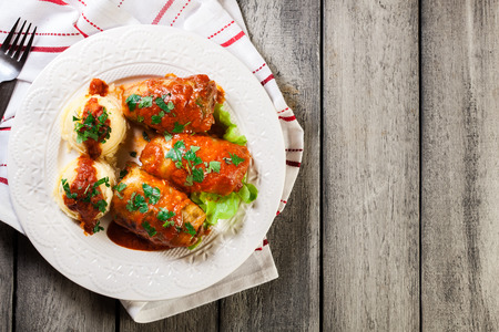 Stuffed cabbage with meat and rice served with boiled potatoes and tomato sauce on white plateの写真素材
