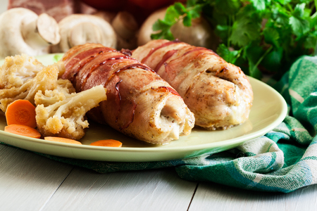 Chicken breast stuffed with champignon, onion and cheese wrapped with bacon served with baked potatoesの写真素材